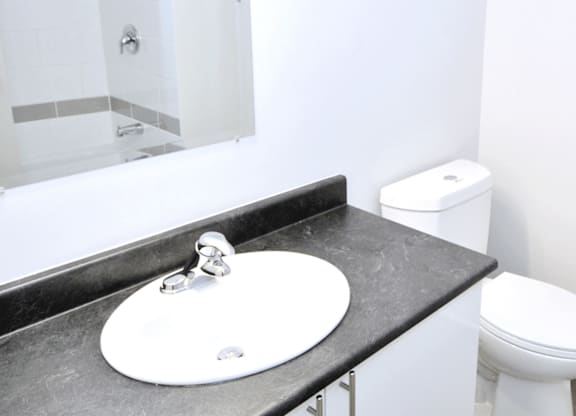 A white sink with a silver faucet on a black countertop in a bathroom.