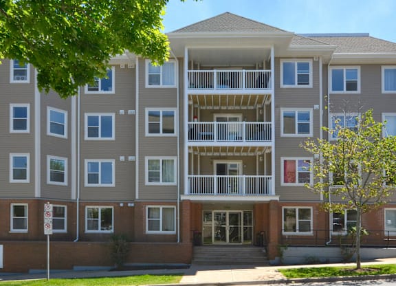 A large apartment building with a tree in front.