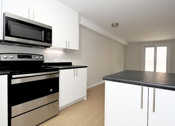 A modern kitchen with black and white appliances and cabinets.