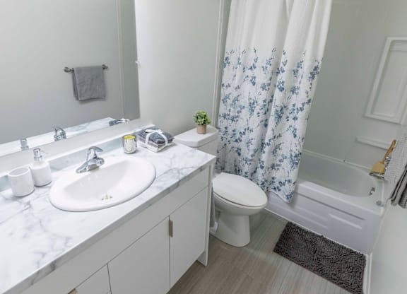 A white bathroom with a sink, toilet, and shower.