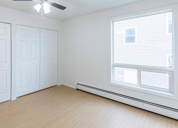 A room with a ceiling fan and a window with blinds.