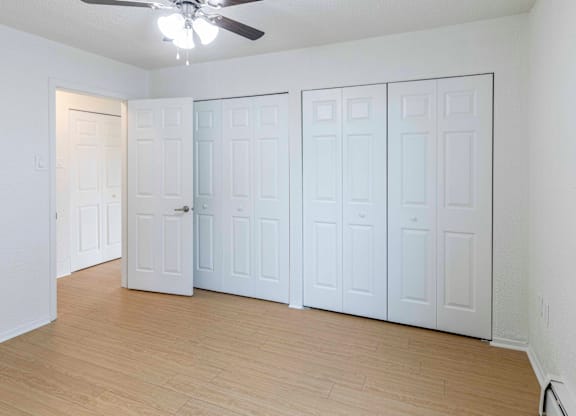 A room with a ceiling fan and white walls.