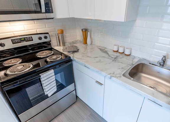 A modern kitchen with a stove, sink, and cabinets.