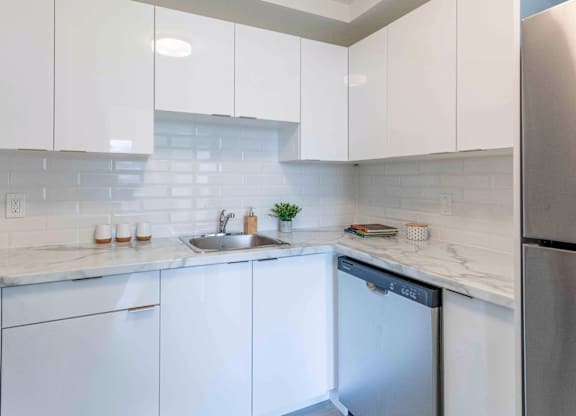A kitchen with white cabinets and a stainless steel refrigerator.