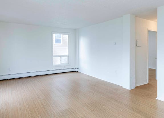 A room with wooden flooring and a window with blinds.