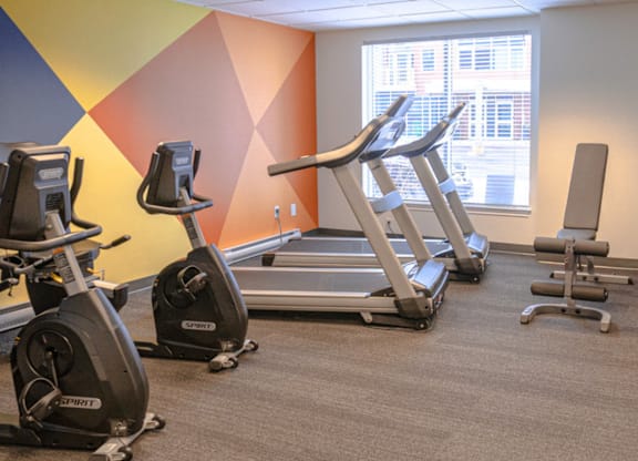A gym with exercise equipment including treadmills and stationary bikes.