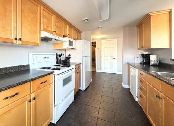A kitchen with wooden cabinets and black countertops.