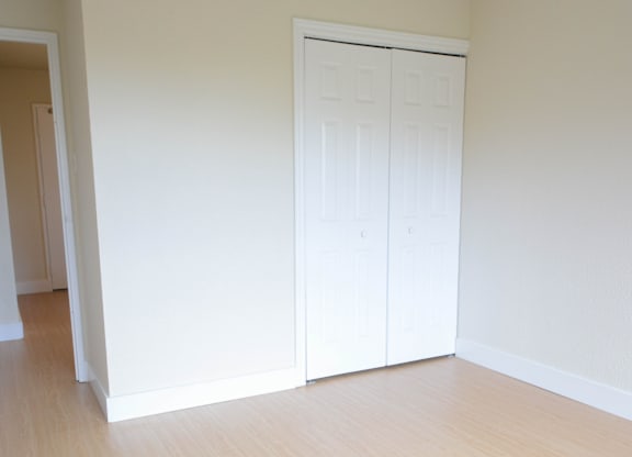 A room with a white door and wooden floor.