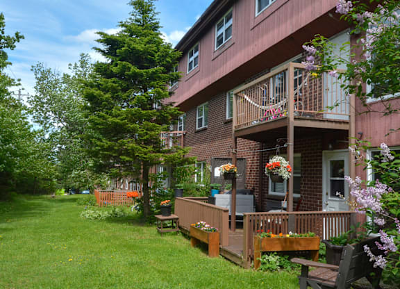 A red building with a balcony and a green lawn in front.