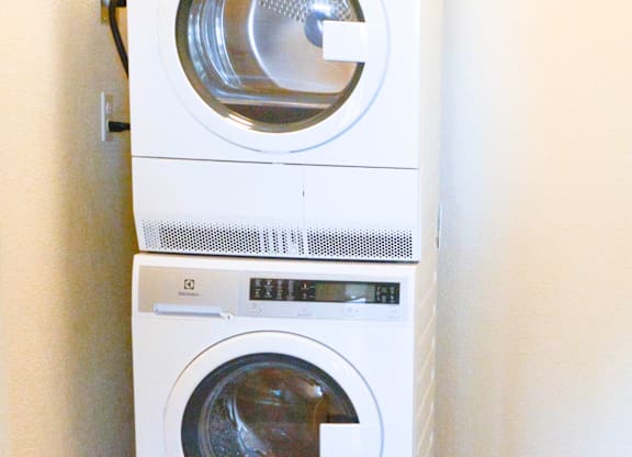A white washing machine is stacked on top of another white washing machine.