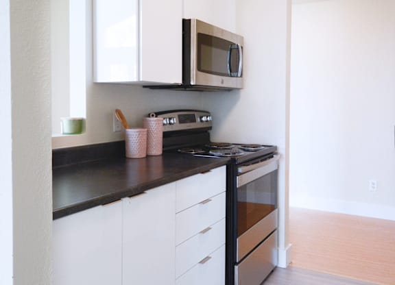 A kitchen with white cabinets and black countertops.