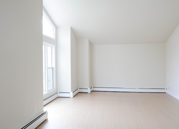 A large empty room with a window on the left side.