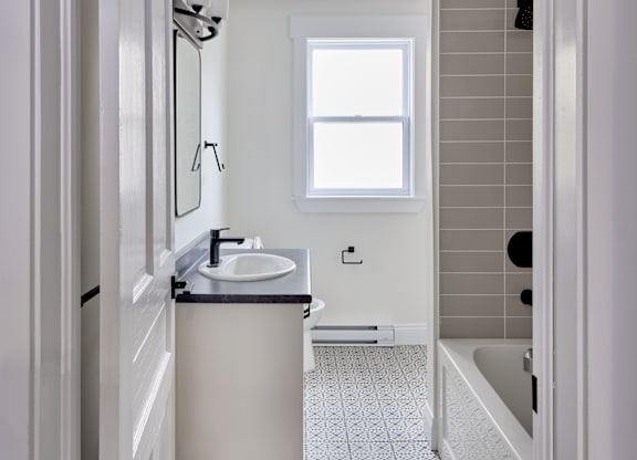 A bathroom with a sink, mirror, and a window.