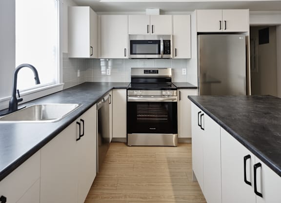 A modern kitchen with white cabinets and black countertops.