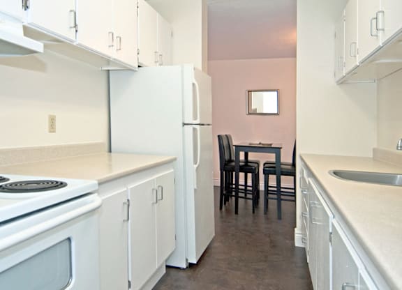 A kitchen with white cabinets and a pink wall.