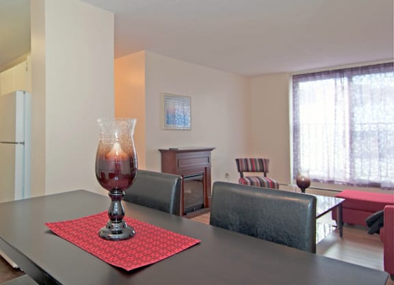A dining table with a red placemat and a glass vase with a candle inside.