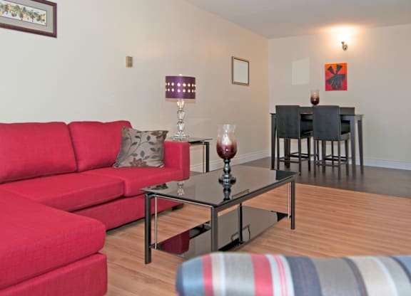 A red couch sits in a living room with a glass table in front of it.
