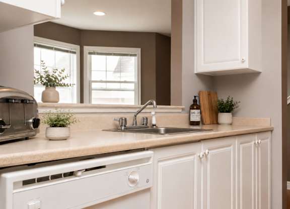 A kitchen with white cabinets and a beige countertop.