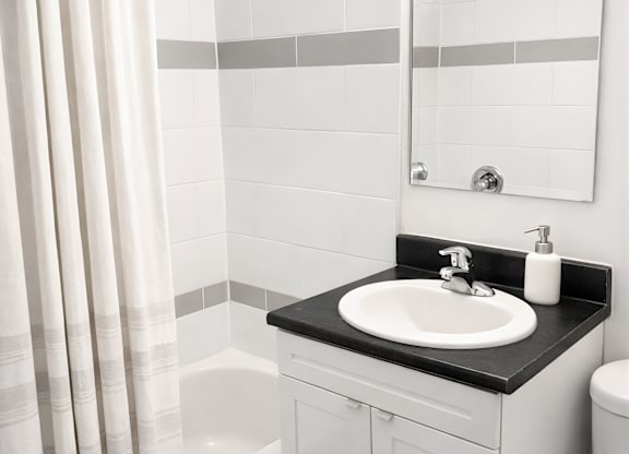 A white bathroom with a black counter top and a white sink.