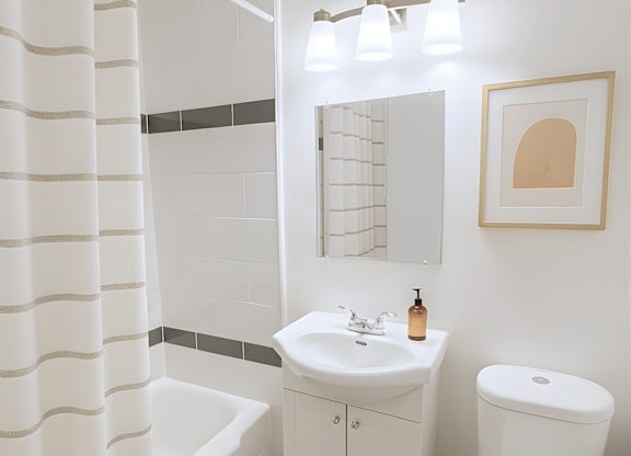 A white bathroom with a toilet, sink, and shower curtain.