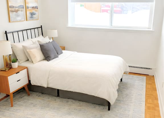 A bedroom with a white bed and a grey rug.