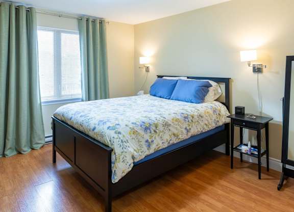 A bedroom with a bed, nightstand, and window.