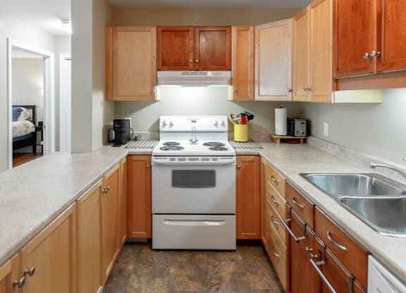 A kitchen with a stove top oven and wooden cabinets.