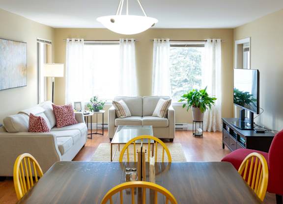A well-lit living room with a dining table and chairs.