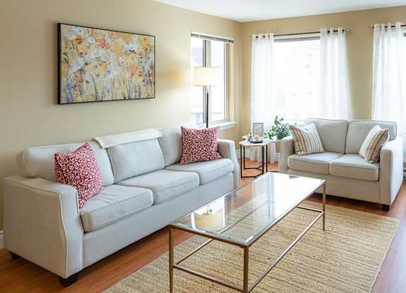 A living room with a white couch and a glass coffee table.