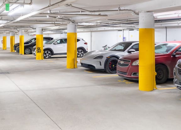 A parking garage with cars parked and yellow poles.