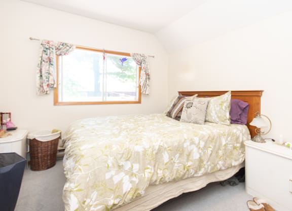 A bedroom with a large bed and a window with curtains.