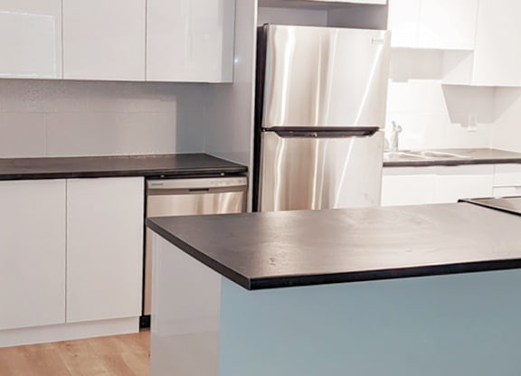 A kitchen with a stainless steel refrigerator and white cabinets.