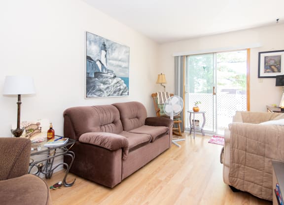 A living room with a brown couch and a painting on the wall.