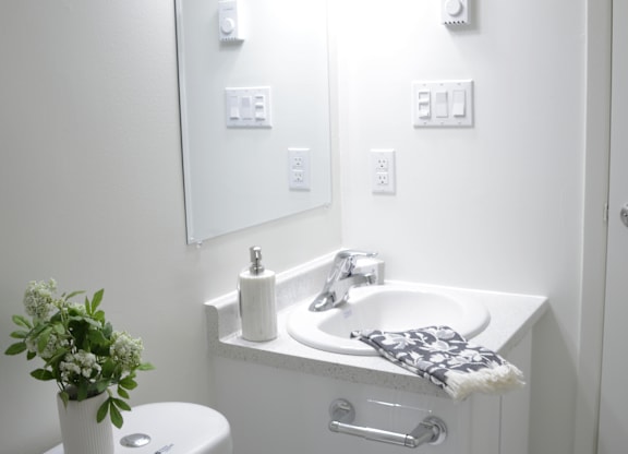 A white bathroom with a toilet, sink, and mirror.