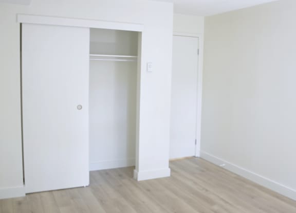 A white door is open to a room with a wooden floor.