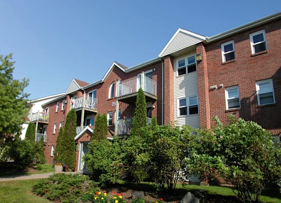 A red brick apartment building with a green lawn in front.