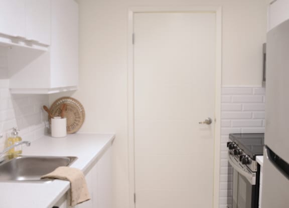 A white kitchen with a sink and a door.