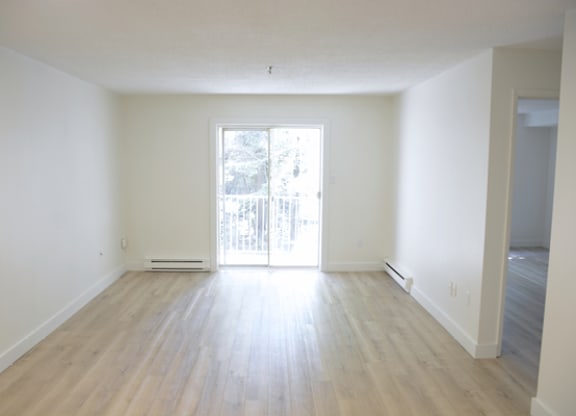 A large empty room with wooden floors and a window.