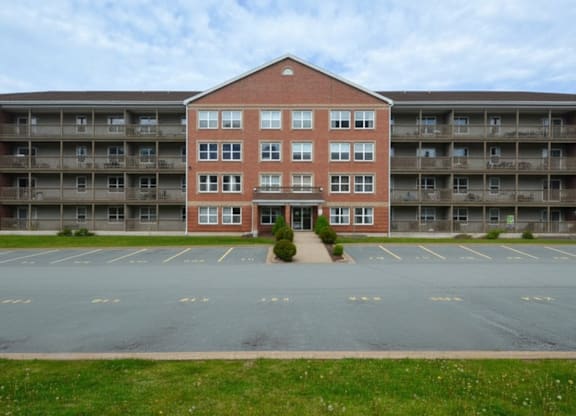 A red brick building with a parking lot in front.