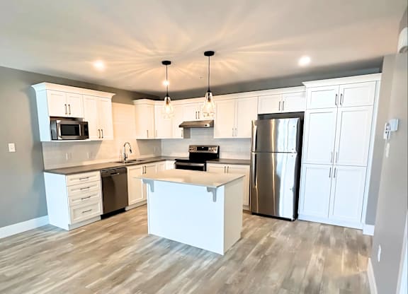 A kitchen with white cabinets and a wooden floor.