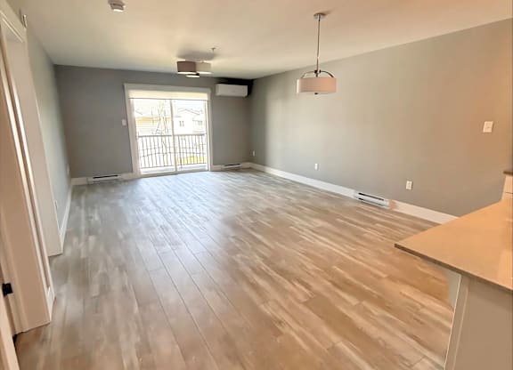 A room with wooden flooring and a large window.