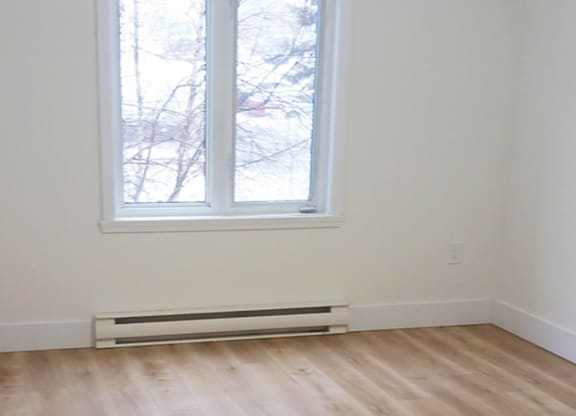 A room with a window and a radiator on the floor.