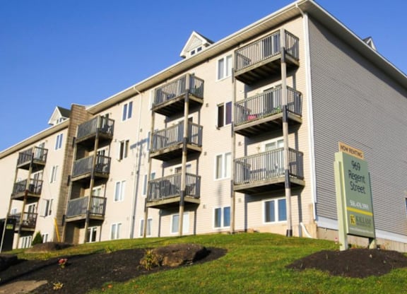 A multi-story apartment building with a sign that reads "Sale" in front of it.