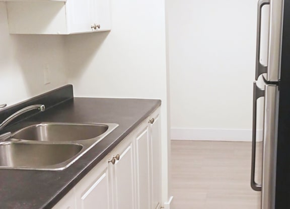 A kitchen with a black countertop and a stainless steel sink.