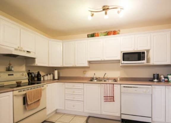 A kitchen with white cabinets and appliances.
