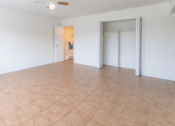 A room with a ceiling fan and tile flooring.