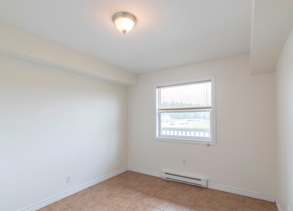 A room with a window and tiled floor.