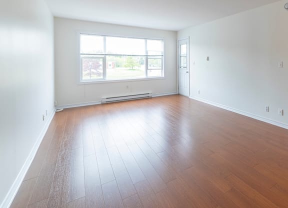 A room with wooden flooring and a large window.