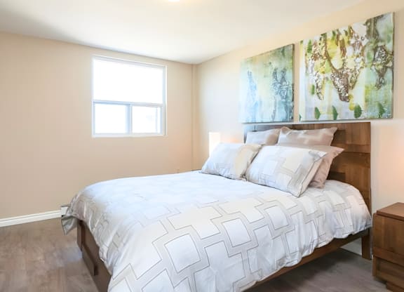 A bedroom with a large bed and two paintings on the wall.