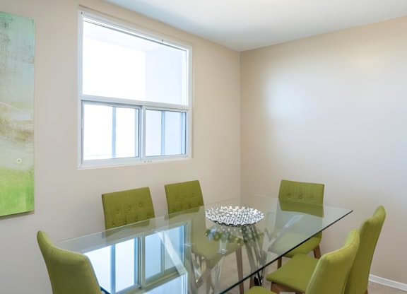 A glass dining table with four chairs and a painting on the wall.